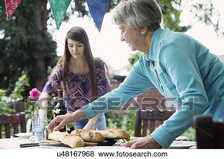 Senior woman setting the table outdoors View Large Photo Image Stock Photo - Senior woman setting the table outdoors. Fotosearch