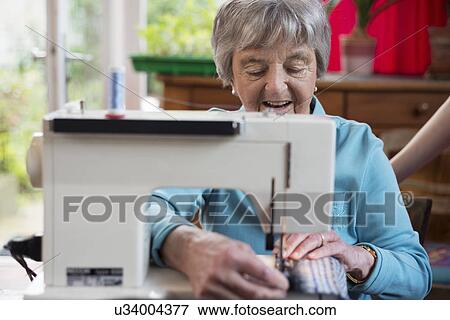 Stock Photo - Senior woman using sewing machine. Fotosearch