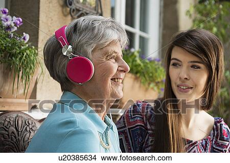 Senior woman wearing headphones with granddaughter View Large Photo Image Picture - Senior woman wearing headphones with granddaughter. Fotosearch