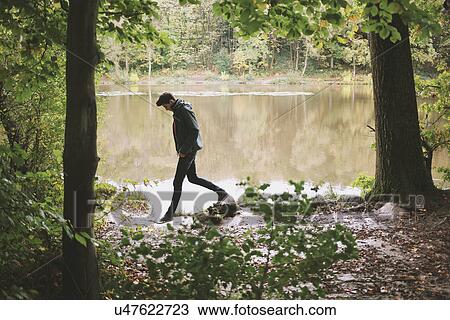 Silhouetted young man strolling along riverbank View Large Photo Image Stock Image - Silhouetted young man strolling along riverbank. Fotosearch