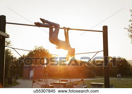 Silhouetted young woman upside down on playground climbing frame at sunset View Large Photo Image Stock Photography - Silhouetted young woman upside down on playground climbing frame at sunset. Fotosearch