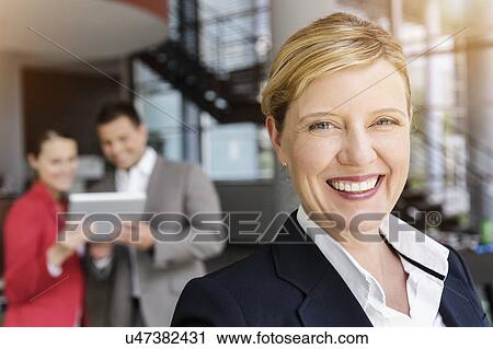 Smiling businesswoman, colleagues in background using digital tablet View Large Photo Image Stock Image - Smiling businesswoman, colleagues in background using digital tablet. Fotosearch