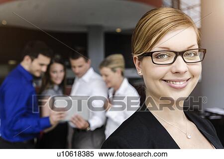 Smiling businesswoman, colleagues in background using digital tablet View Large Photo Image Stock Photography - Smiling businesswoman, colleagues in background using digital tablet. Fotosearch