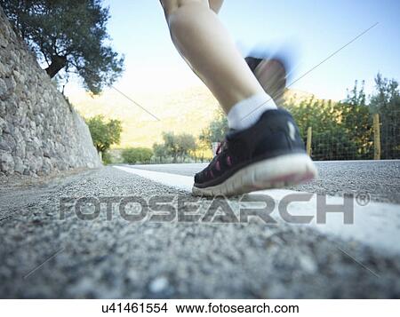 Picture - Surface level view of teenage girls legs running on road, Majorca, Spain. Fotosearch