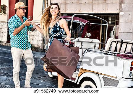 Stock Photo - Taxi driver giving helping hand to young woman stepping from taxi, Cagliari, Sardinia, Italy. Fotosearch