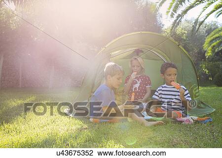 Three children eating ice lollies in garden tent View Large Photo Image Stock Image - Three children eating ice lollies in garden tent. Fotosearch