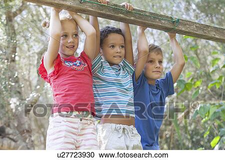 Three children holding onto fence looking away View Large Photo Image Stock Image - Three children holding onto fence looking away. Fotosearch