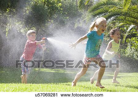 Three children in garden chasing each other with water sprinkler View Large Photo Image Stock Image - Three children in garden chasing each other with water sprinkler. Fotosearch