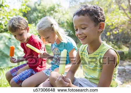 Three children in garden eating ice lollies View Large Photo Image Stock Photo - Three children in garden eating ice lollies. Fotosearch