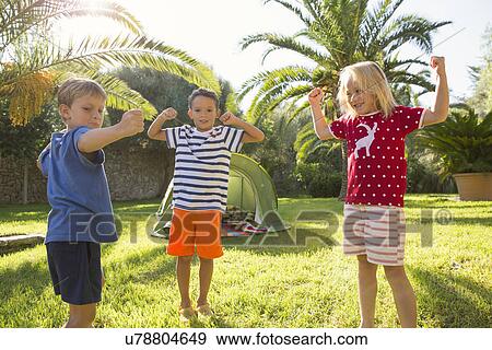 Stock Photo - Three children in garden flexing muscles. Fotosearch