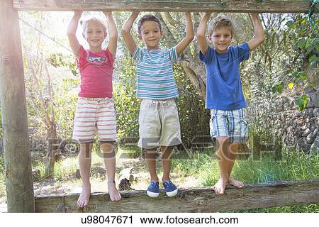 Three children in garden standing on fence View Large Photo Image Stock Image - Three children in garden standing on fence. Fotosearch