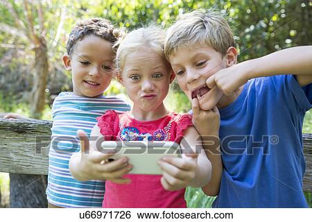 Three children in garden taking selfie on smartphone View Large Photo Image Stock Photograph - Three children in garden taking selfie on smartphone. Fotosearch