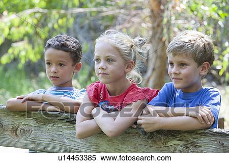 Three children leaning on fence looking away View Large Photo Image Stock Photography - Three children leaning on fence looking away. Fotosearch