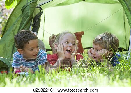 Three children lying chatting in garden tent View Large Photo Image Stock Image - Three children lying chatting in garden tent. Fotosearch