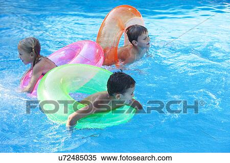 Three children playing in garden swimming pool with inflatable rings View Large Photo Image Stock Photography - Three children playing in garden swimming pool with inflatable rings. Fotosearch