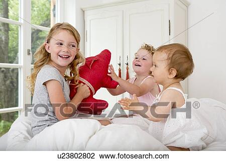 Three girls playing on bed with soft toy View Large Photo Image Stock Image - Three girls playing on bed with soft toy. Fotosearch