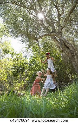 Three Girls Playing On Tree Tire Swing In Garden Picture