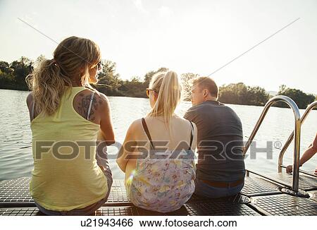 Three young adult friends gazing from riverside pier View Large Photo Image Stock Photograph - Three young adult friends gazing from riverside pier. Fotosearch