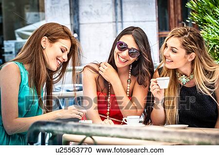 Stock Image - Three young female friends drinking espresso at sidewalk cafe, Cagliari, Sardinia, Italy. Fotosearch