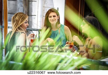 Three young female friends having cocktails at sidewalk cafe, Cagliari, Sardinia, Italy View Large Photo Image Stock Photo - Three young female friends having cocktails at sidewalk cafe, Cagliari, Sardinia, Italy. Fotosearch