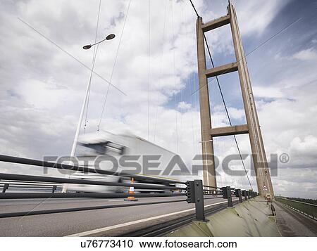 Stock Image - Traffic on suspension bridge. The Humber Bridge, UK was built in 1981 and at the time was the world's largest single-span suspension bridge. Fotosearch