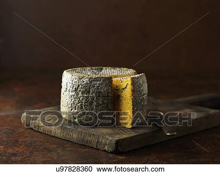 Stock Image - Truckle of blacksticks blue cheese on chopping board. Fotosearch