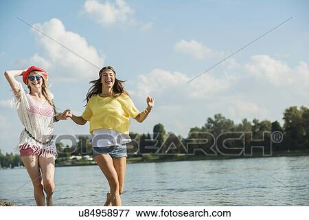 Two female friends running by lake View Large Photo Image Stock Photo - Two female friends running by lake. Fotosearch