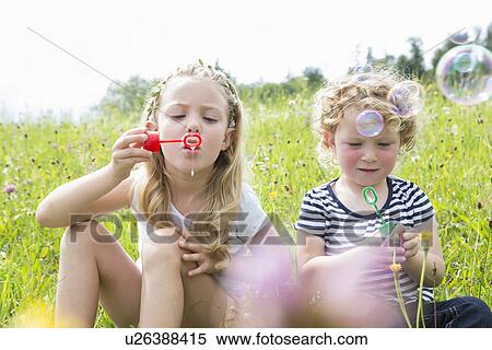 Two girls blowing bubbles View Large Photo Image Stock Photography - Two girls blowing bubbles. Fotosearch