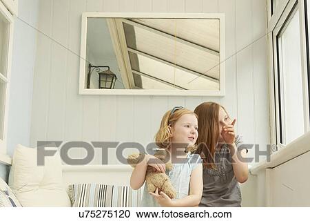 Two sisters pointing and looking out of holiday apartment window View Large Photo Image Stock Image - Two sisters pointing and looking out of holiday apartment window. Fotosearch