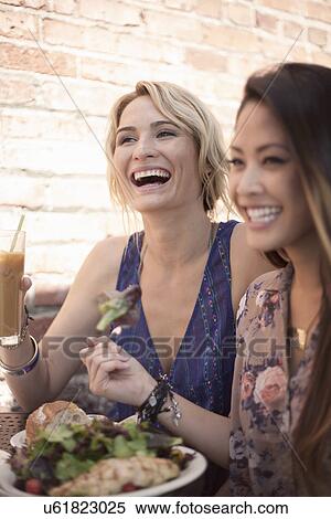 Stock Photography - Two women, laughing, having lunch together. Fotosearch