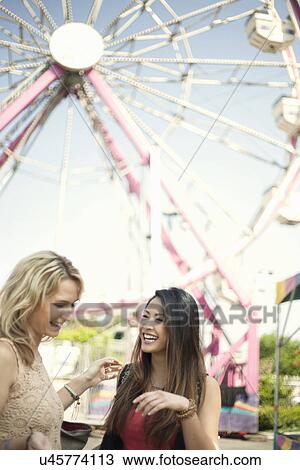 Two women standing in front of feris wheel, laughing View Large Photo Image Stock Image - Two women standing in front of feris wheel, laughing. Fotosearch