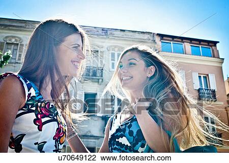 Two young female friends chatting on street, Cagliari, Sardinia, Italy View Large Photo Image Stock Image - Two young female friends chatting on street, Cagliari, Sardinia, Italy. Fotosearch