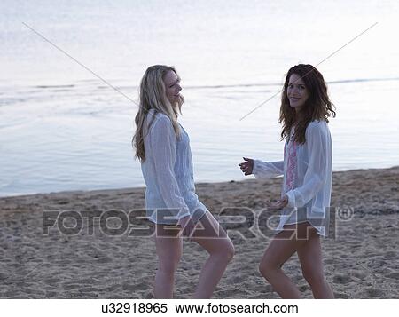 Two young women friends standing chatting on beach at dusk, Williamstown, Melbourne, Australia View Large Photo Image Stock Photography - Two young women friends standing chatting on beach at dusk, Williamstown, Melbourne, Australia. Fotosearch