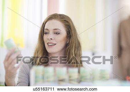 Stock Image - Woman browsing products on display shelf. Fotosearch