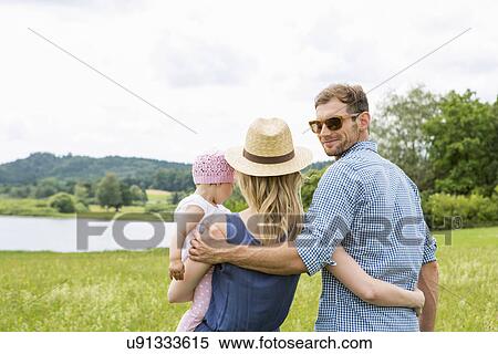 Woman holding baby daughter, man looking over shoulder View Large Photo Image Stock Photography - Woman holding baby daughter, man looking over shoulder. Fotosearch
