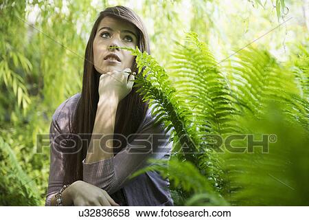 Stock Photo - Woman kneeling by fern. Fotosearch