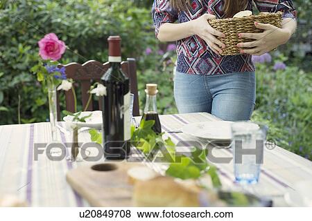 Stock Photo - Woman setting the table outdoors. Fotosearch