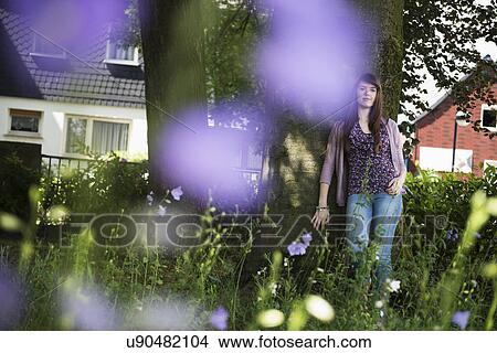 Picture - Woman standing by tree. Fotosearch