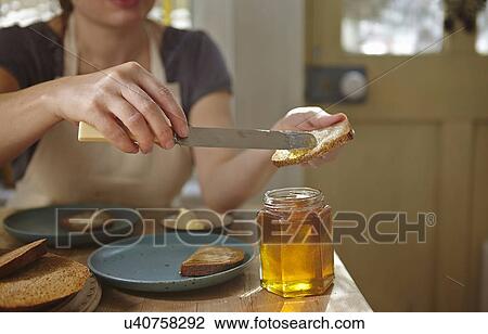 Stock Image - Woman tasting freshly extracted honey on bread. Fotosearch