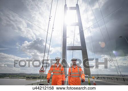 Stock Photo - Workers walking along roadway of suspension bridge. The Humber Bridge, UK was built in 1981 and at the time was the world's largest single-span suspension bridge. Fotosearch