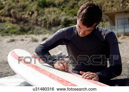 Young adult male surfer waxing board View Large Photo Image Stock Photograph - Young adult male surfer waxing board. Fotosearch