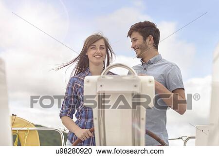 Young couple at the helm of yacht under bright sunlight View Large Photo Image Stock Image - Young couple at the helm of yacht under bright sunlight. Fotosearch