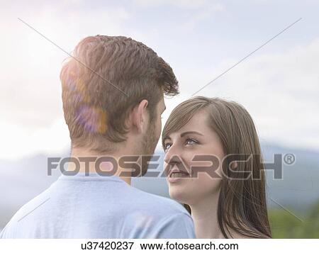 Stock Photo - Young couple face to face under bright sunny sky. Fotosearch