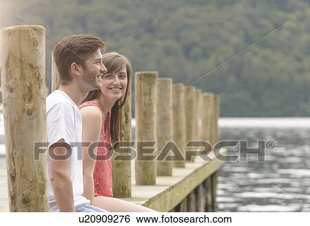 Young couple laughing together on jetty over lake View Large Photo Image Stock Photograph - Young couple laughing together on jetty over lake. Fotosearch