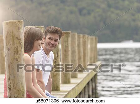 Young couple laughing together on jetty over lake View Large Photo Image Stock Photograph - Young couple laughing together on jetty over lake. Fotosearch