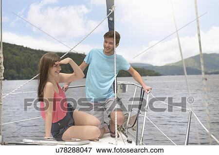 Young couple on bow of yacht sailing on lake under bright sunlight View Large Photo Image Stock Photo - Young couple on bow of yacht sailing on lake under bright sunlight. Fotosearch
