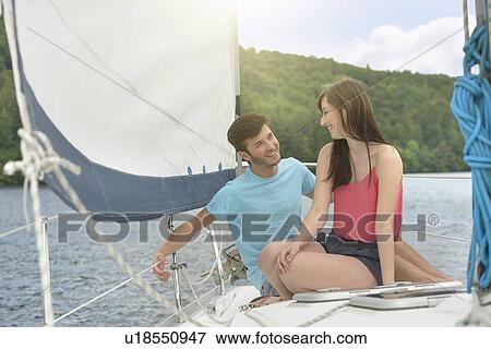 Young couple sailing on sunlit yacht over lake, smiling View Large Photo Image Stock Photo - Young couple sailing on sunlit yacht over lake, smiling. Fotosearch