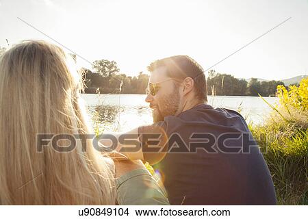 Young couple sitting on riverbank View Large Photo Image Picture - Young couple sitting on riverbank. Fotosearch