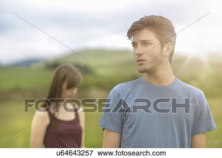 Young couple standing apart and looking away in rural landscape under bright sunny sky View Large Photo Image Stock Photo - Young couple standing apart and looking away in rural landscape under bright sunny sky. Fotosearch