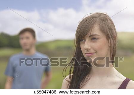 Stock Photograph - Young couple standing apart and looking away in rural landscape, close up. Fotosearch